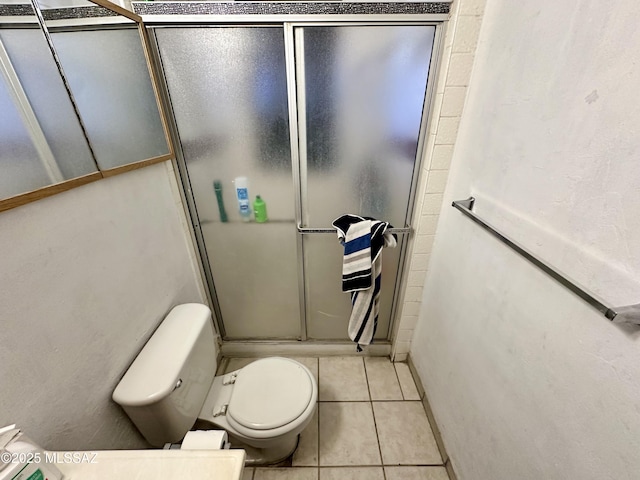 full bath featuring a shower stall, toilet, and tile patterned floors