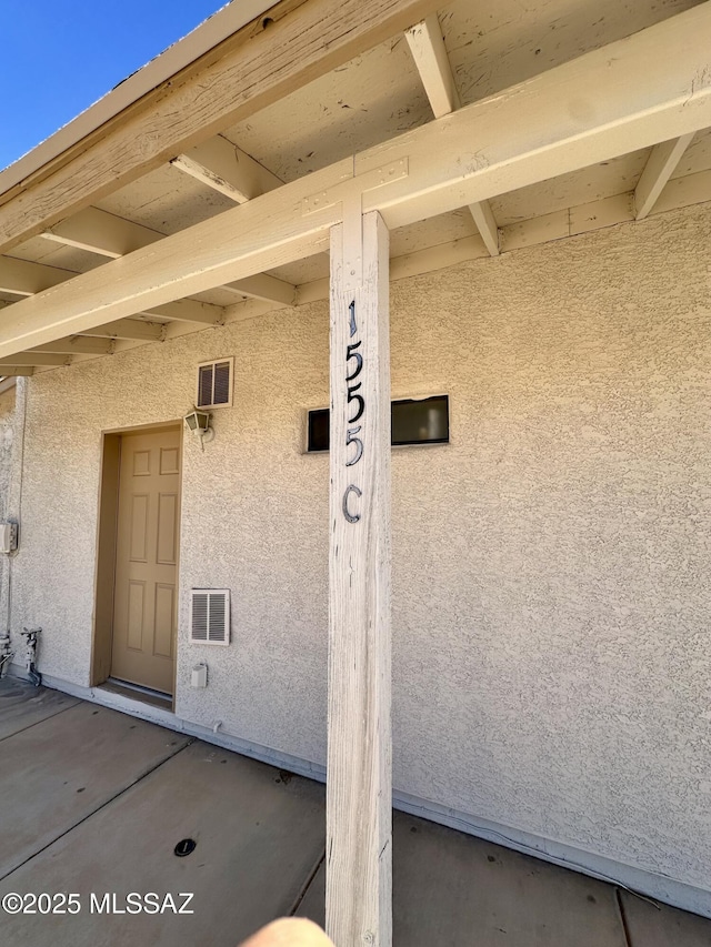 view of exterior entry featuring visible vents and stucco siding