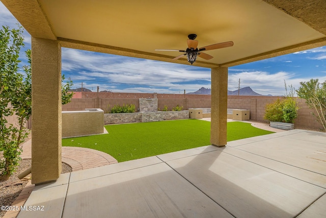 view of patio featuring a ceiling fan, a fenced backyard, and a mountain view