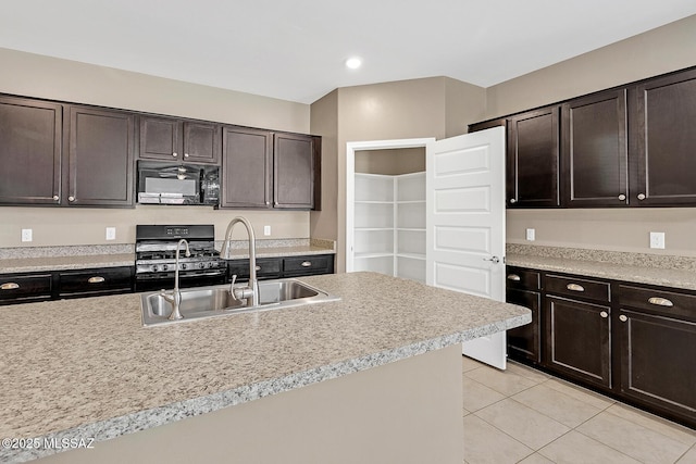 kitchen featuring gas range, light countertops, black microwave, a sink, and light tile patterned flooring