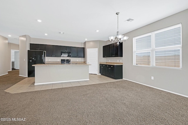 kitchen featuring light countertops, light colored carpet, visible vents, dark cabinetry, and black appliances