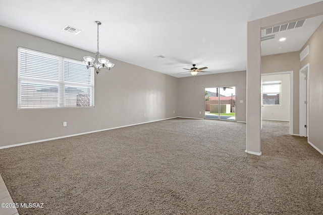 carpeted empty room featuring ceiling fan with notable chandelier, visible vents, and baseboards