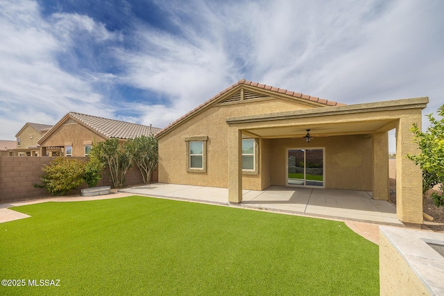 rear view of property featuring a ceiling fan, a patio, fence, a yard, and stucco siding