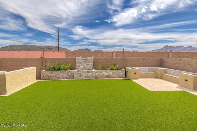 view of yard with a fenced backyard, a patio, and a mountain view