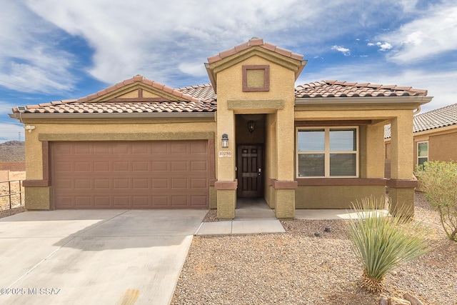 mediterranean / spanish-style house featuring a garage, a tile roof, concrete driveway, and stucco siding