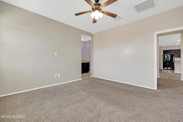 carpeted spare room featuring a ceiling fan, visible vents, and baseboards