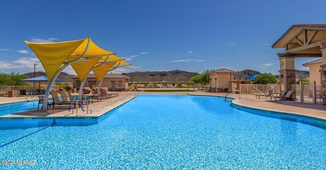 community pool featuring a mountain view, fence, and a patio