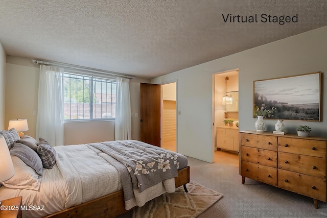 bedroom featuring ensuite bathroom, light carpet, and a textured ceiling