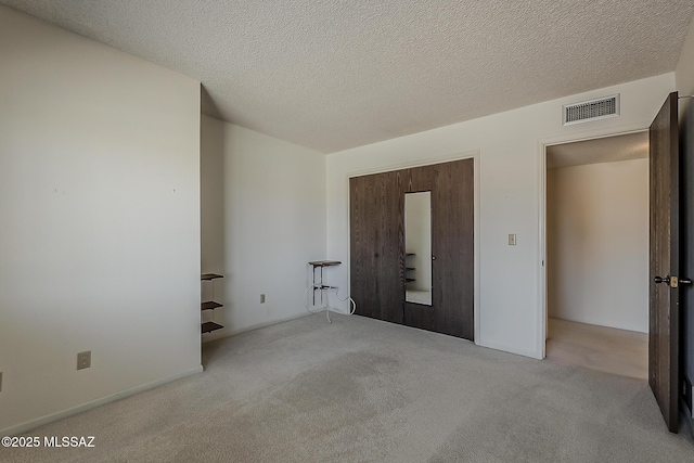 unfurnished bedroom featuring visible vents, carpet, and a textured ceiling