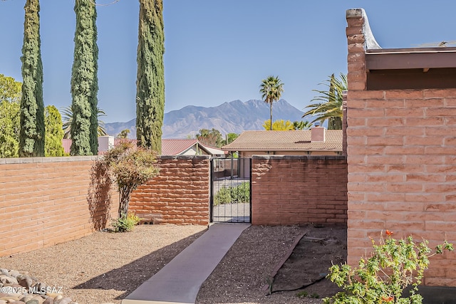 view of yard featuring a mountain view, fence, and a gate