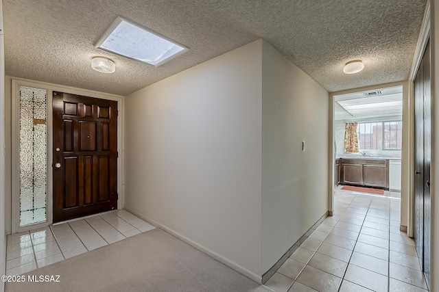 entryway with light tile patterned floors, baseboards, visible vents, a textured ceiling, and a skylight