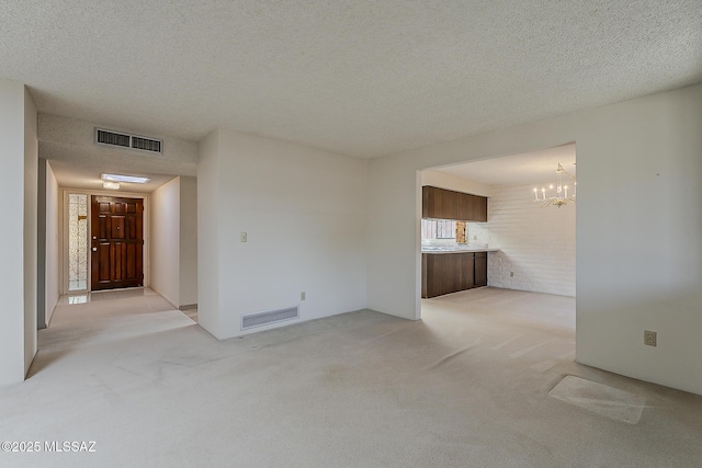 unfurnished living room featuring visible vents, light colored carpet, and a notable chandelier