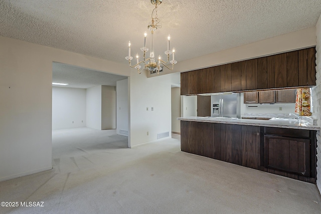 kitchen with stainless steel fridge with ice dispenser, a peninsula, light colored carpet, and light countertops