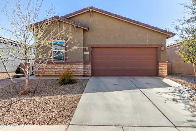 view of front of property with driveway, stone siding, an attached garage, and stucco siding