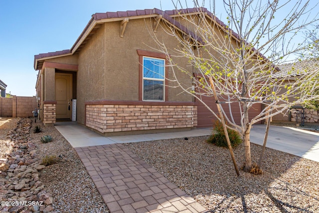 view of front of home with driveway, a tile roof, fence, and stucco siding