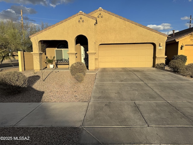 view of front facade featuring driveway, an attached garage, a tiled roof, and stucco siding