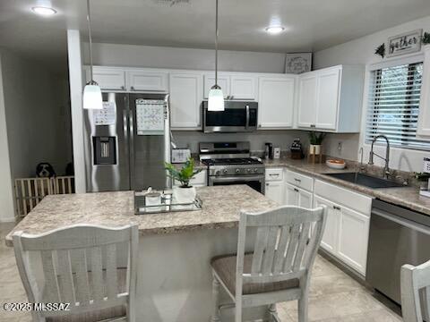 kitchen featuring a breakfast bar area, appliances with stainless steel finishes, white cabinets, and a sink