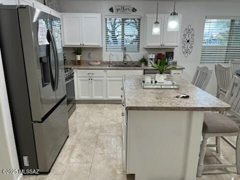 kitchen featuring a center island, white cabinetry, a sink, gas range, and stainless steel fridge with ice dispenser