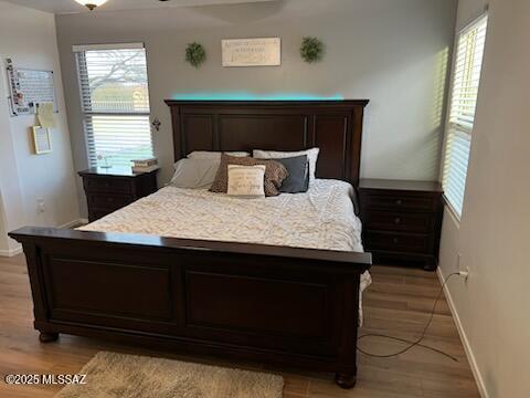 bedroom featuring multiple windows, light wood-type flooring, and baseboards