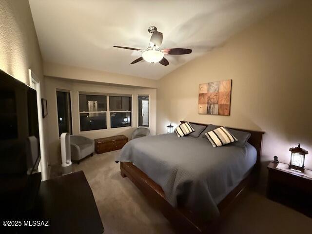 bedroom with ceiling fan, vaulted ceiling, and carpet flooring