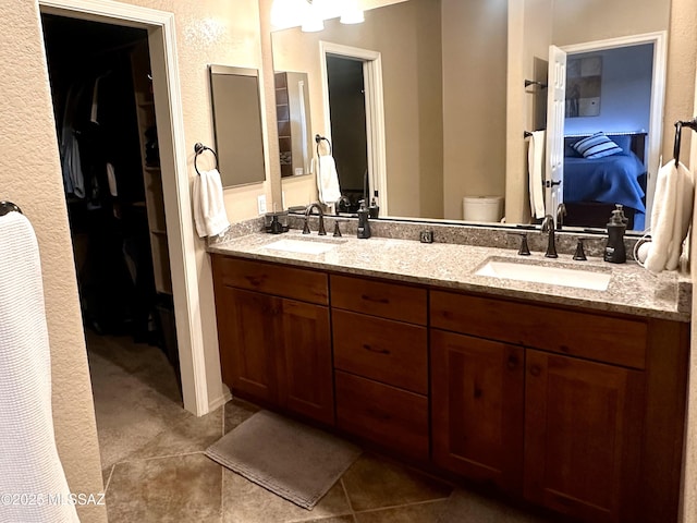 ensuite bathroom featuring double vanity, tile patterned floors, a sink, and connected bathroom