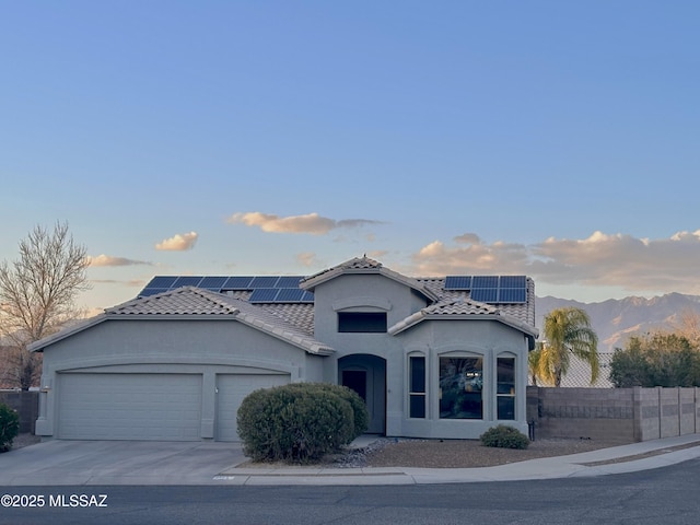 mediterranean / spanish home featuring a garage, a tile roof, fence, driveway, and stucco siding