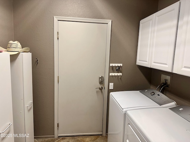 clothes washing area featuring cabinet space, washer and clothes dryer, and a textured wall