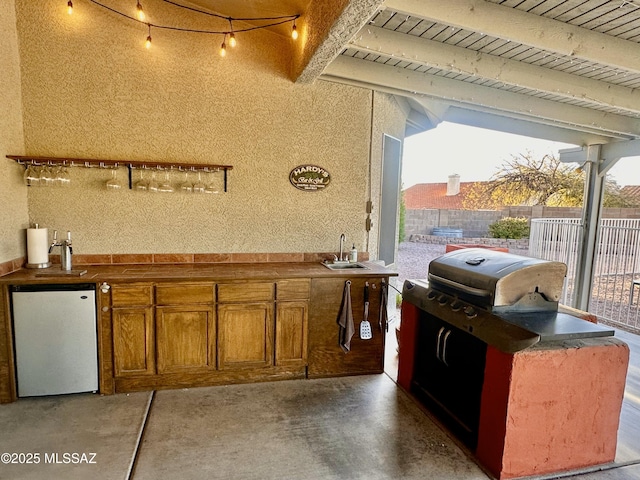 view of patio / terrace featuring exterior kitchen, a grill, fence, and a sink