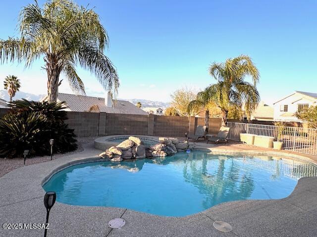 view of swimming pool with a fenced backyard, a fenced in pool, and an in ground hot tub