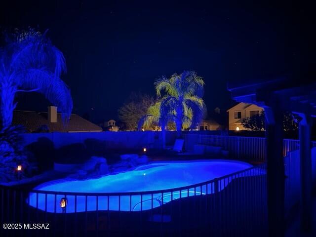 pool at night featuring a fenced in pool and a fenced backyard