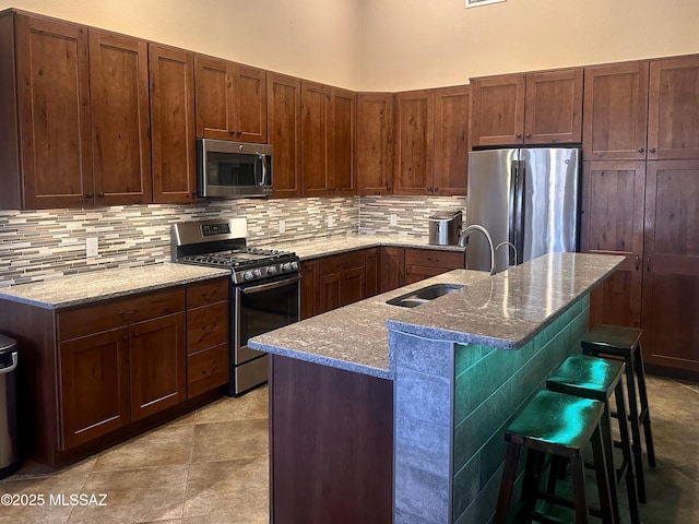 kitchen with stainless steel appliances, stone countertops, a sink, and backsplash