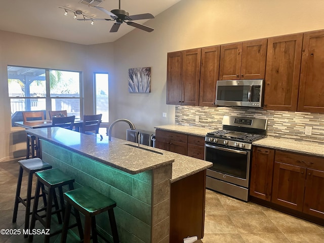 kitchen with lofted ceiling, a sink, light stone countertops, stainless steel appliances, and backsplash