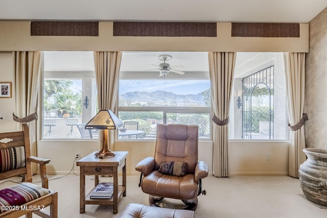 sitting room featuring plenty of natural light, light colored carpet, a mountain view, and baseboards