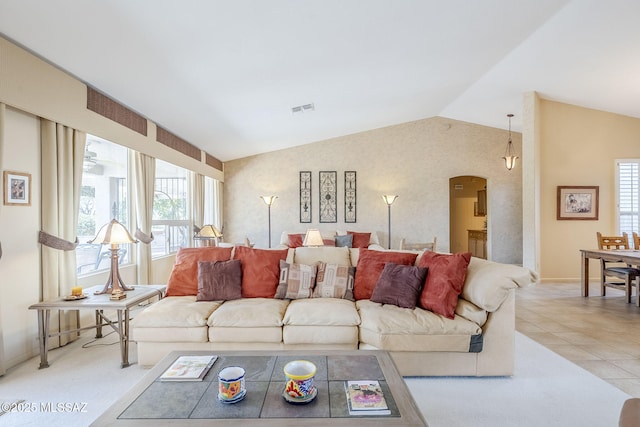 living room featuring light tile patterned floors, visible vents, lofted ceiling, and arched walkways