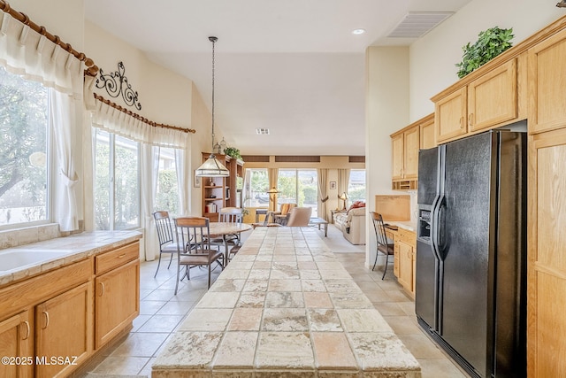 kitchen with tile countertops, light brown cabinets, visible vents, high vaulted ceiling, and black fridge with ice dispenser