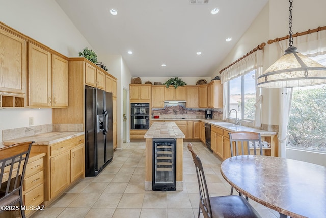 kitchen featuring black appliances, beverage cooler, light brown cabinetry, a sink, and a center island