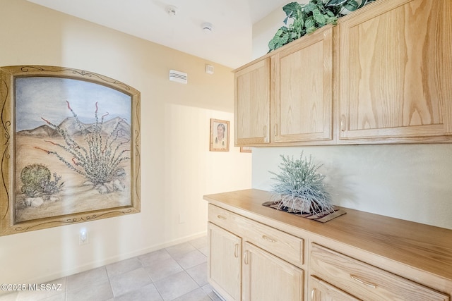 kitchen with light brown cabinetry, light tile patterned floors, light countertops, and baseboards