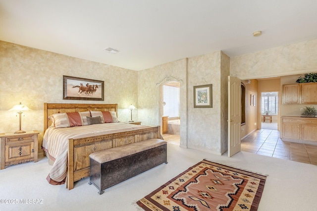 bedroom featuring light tile patterned floors, visible vents, and ensuite bathroom