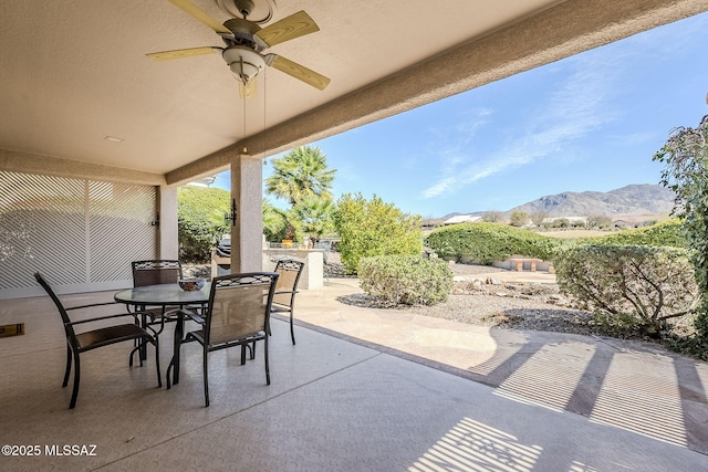 view of patio / terrace featuring a mountain view, outdoor dining space, and a ceiling fan