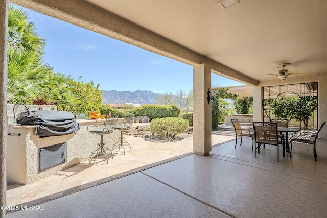 view of patio / terrace with outdoor dining space, a mountain view, exterior kitchen, and ceiling fan