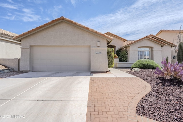 view of front of property with stucco siding, decorative driveway, a garage, and a tile roof