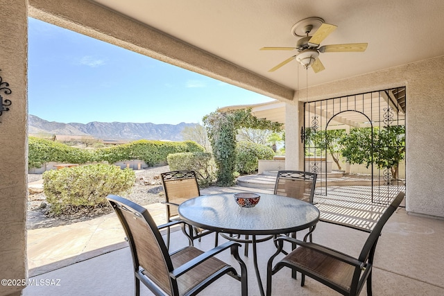 view of patio featuring outdoor dining space, a ceiling fan, and a mountain view