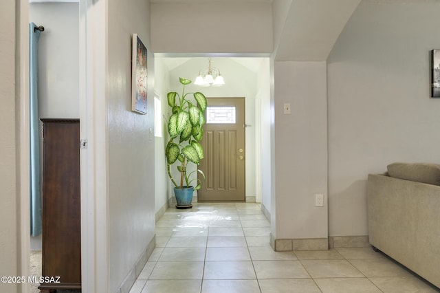 foyer entrance with light tile patterned floors, baseboards, and an inviting chandelier