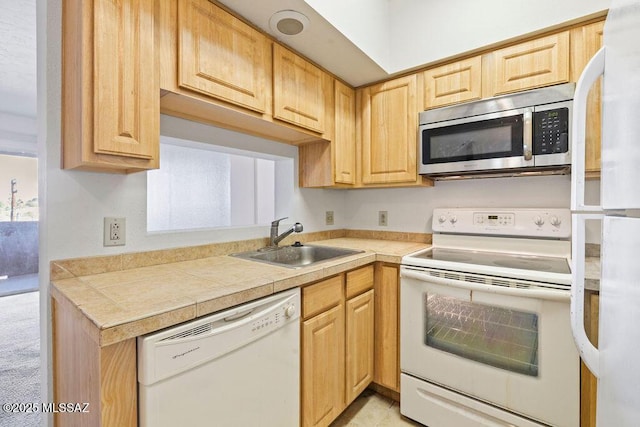 kitchen featuring light countertops, white appliances, light brown cabinets, and a sink