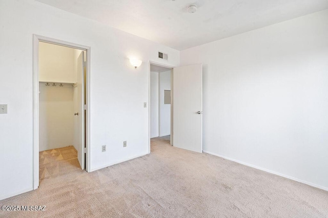 unfurnished bedroom with a closet, visible vents, a spacious closet, and carpet flooring