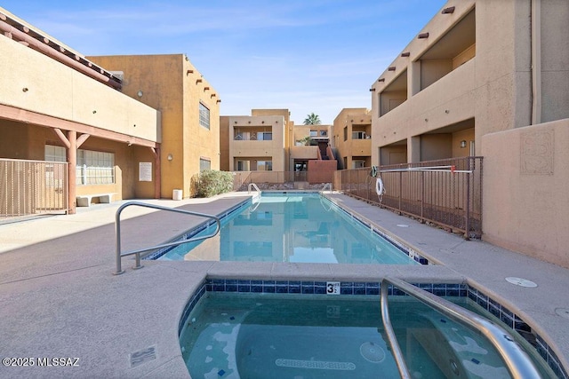 community pool with fence and a hot tub