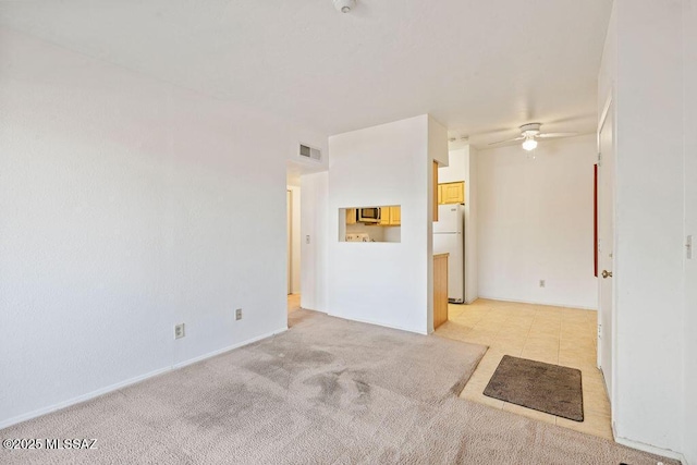 spare room featuring a ceiling fan, visible vents, and light carpet