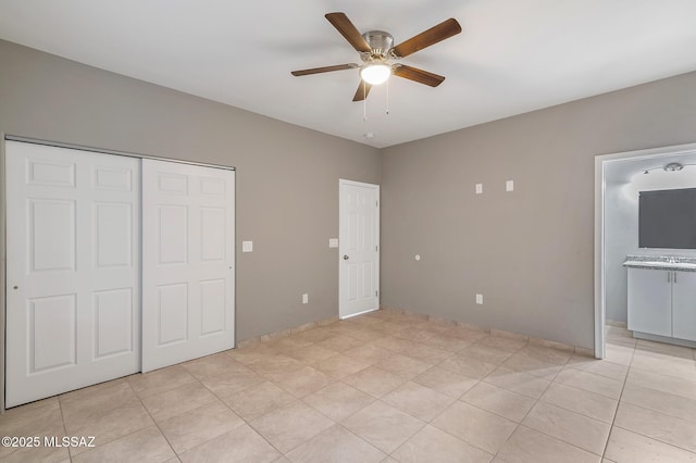 unfurnished bedroom featuring ensuite bath, light tile patterned floors, ceiling fan, and a closet