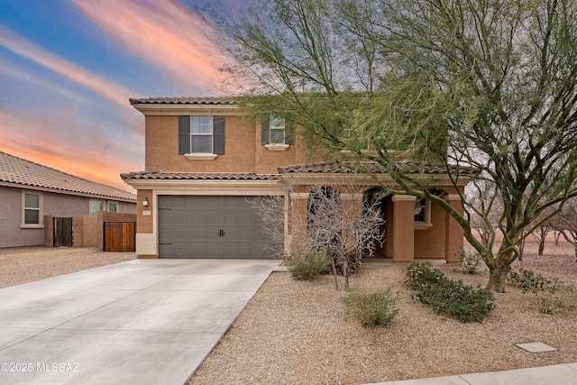 view of front of house with concrete driveway, a tiled roof, an attached garage, fence, and stucco siding