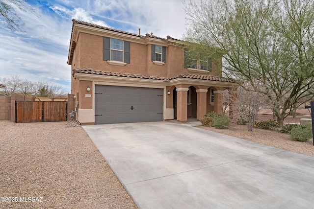 mediterranean / spanish house featuring concrete driveway, an attached garage, fence, and stucco siding